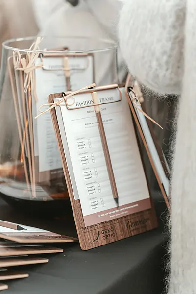 Holzklemmbrett mit Bewertungsbogen und Bleistift neben flauschigem Strick