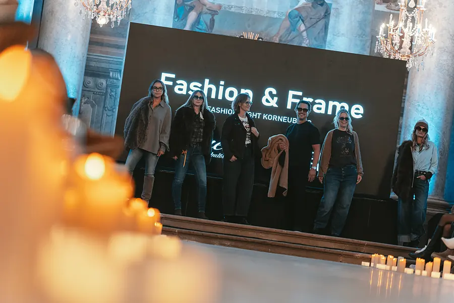 Models in Jeans und dunklen Jacken stehen auf der Bühne, davor Kerzen