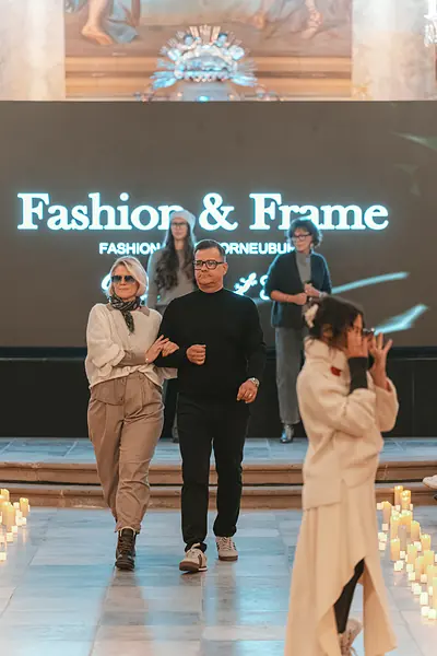 Zwei Models gehen eingehakt auf die Kamera zu, daneben fotografiert eine Person